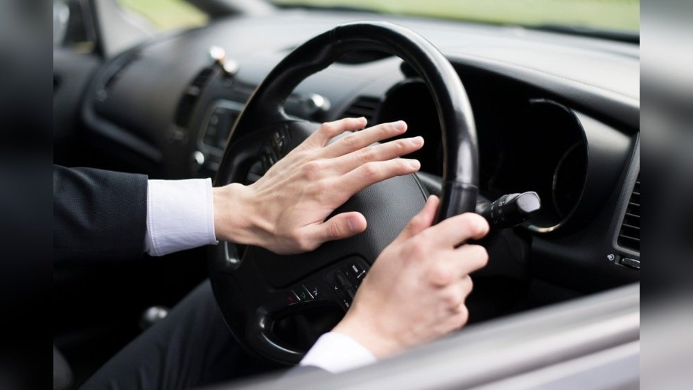 Driver pressing car horn on steering wheel - car horn maintenance and replacement guide